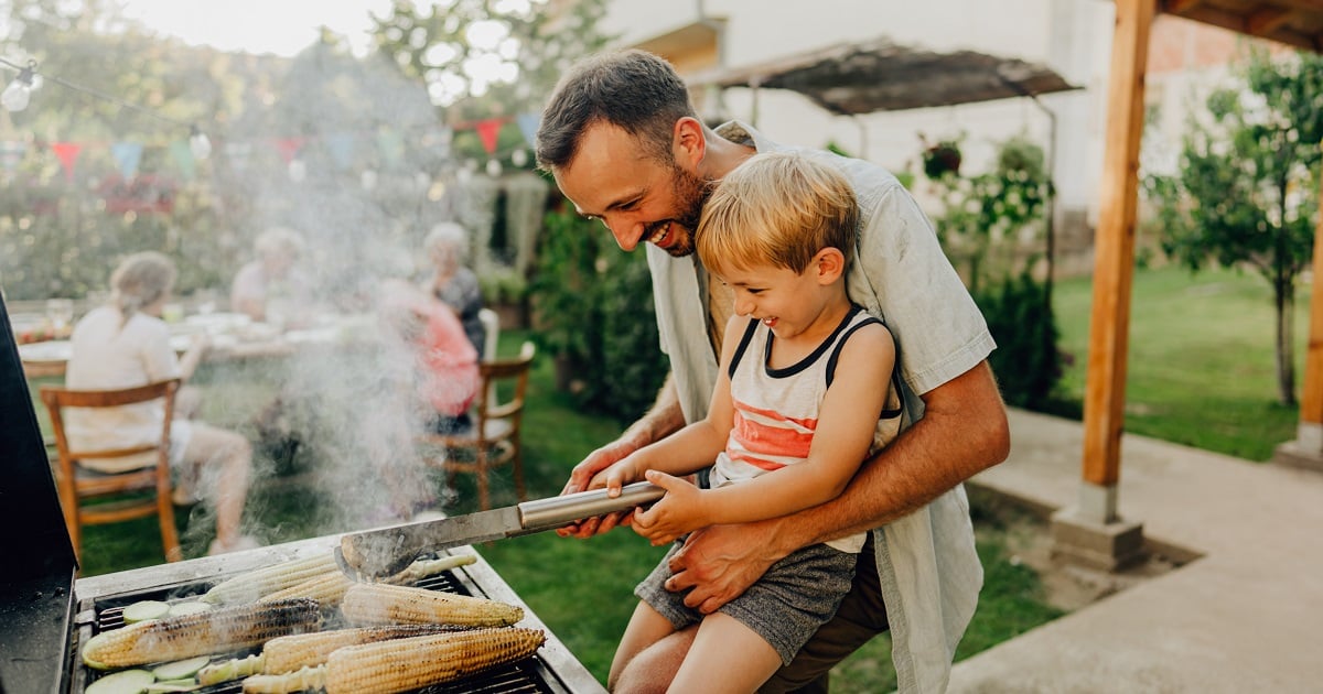 A father and son at the grill together.