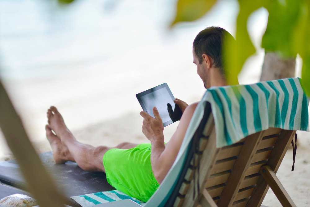 Man relaxing with tablet at beach