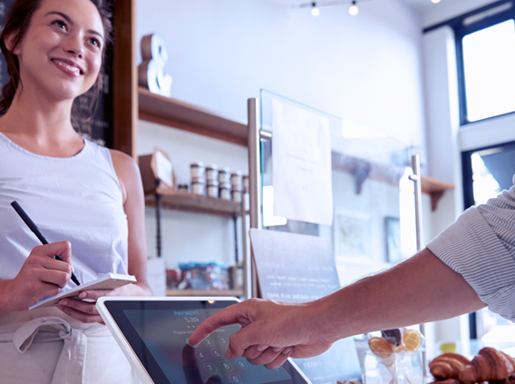 Woman taking order while customer pays on device